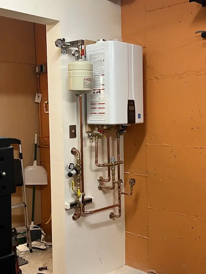 Plumbing technician inspecting water heater connections in Plaistow